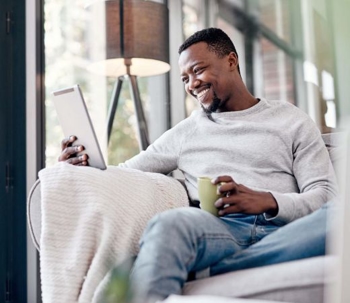 Man smiling looking at tablet.